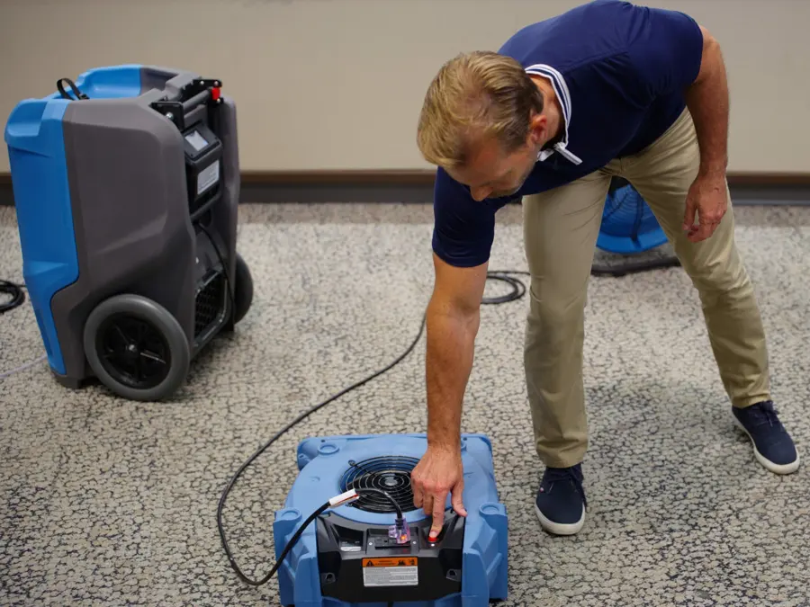 A technician setting air movers and a dehumidifier for structural drying in a Forest Park, GA home