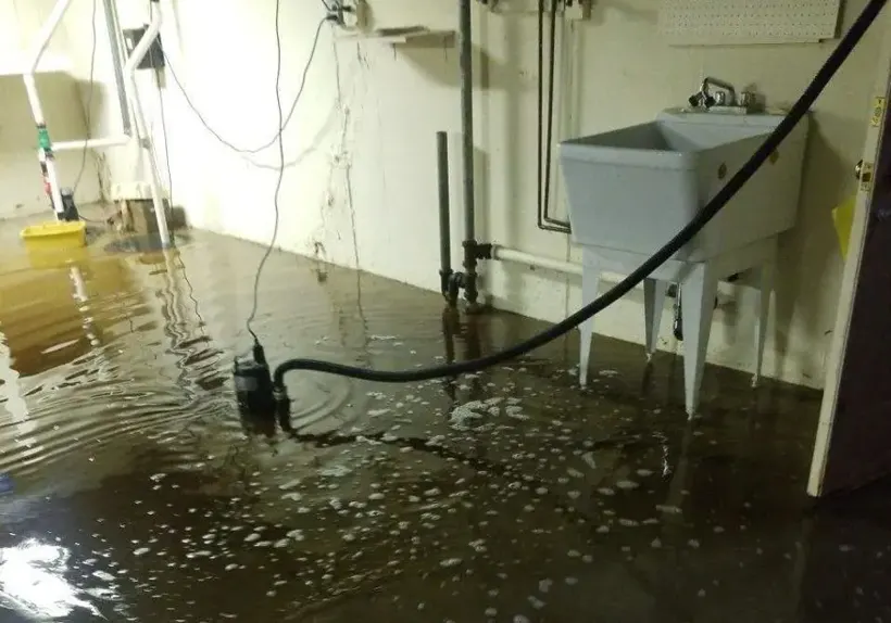 Sump pump and hose in a flooded lower level of a Forest Park, GA home